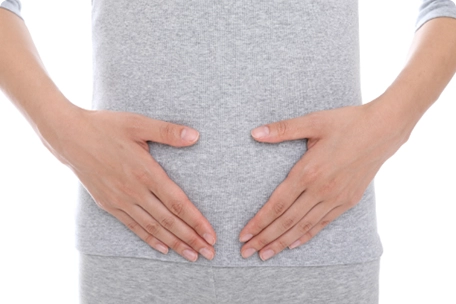 女性がお腹周りを押さえている画像